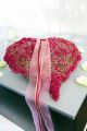 Das Herz aus pinkfarbener Erica gracilis, Silberdraht und Dekobändern als Sinnbild für große Gefühle ist die perfekte Tischdekoration bei einer romantischen Hochzeitsfeier. © Azerca